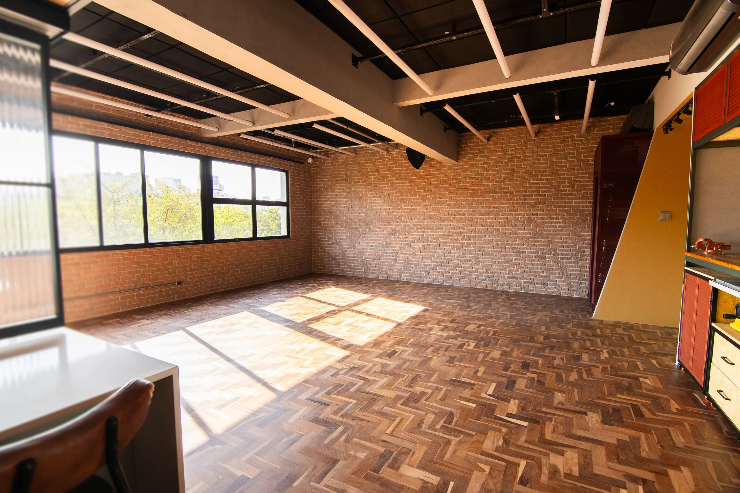 Empty loft with a brick wall and the sun drawing the window frame onto the parquet floor.