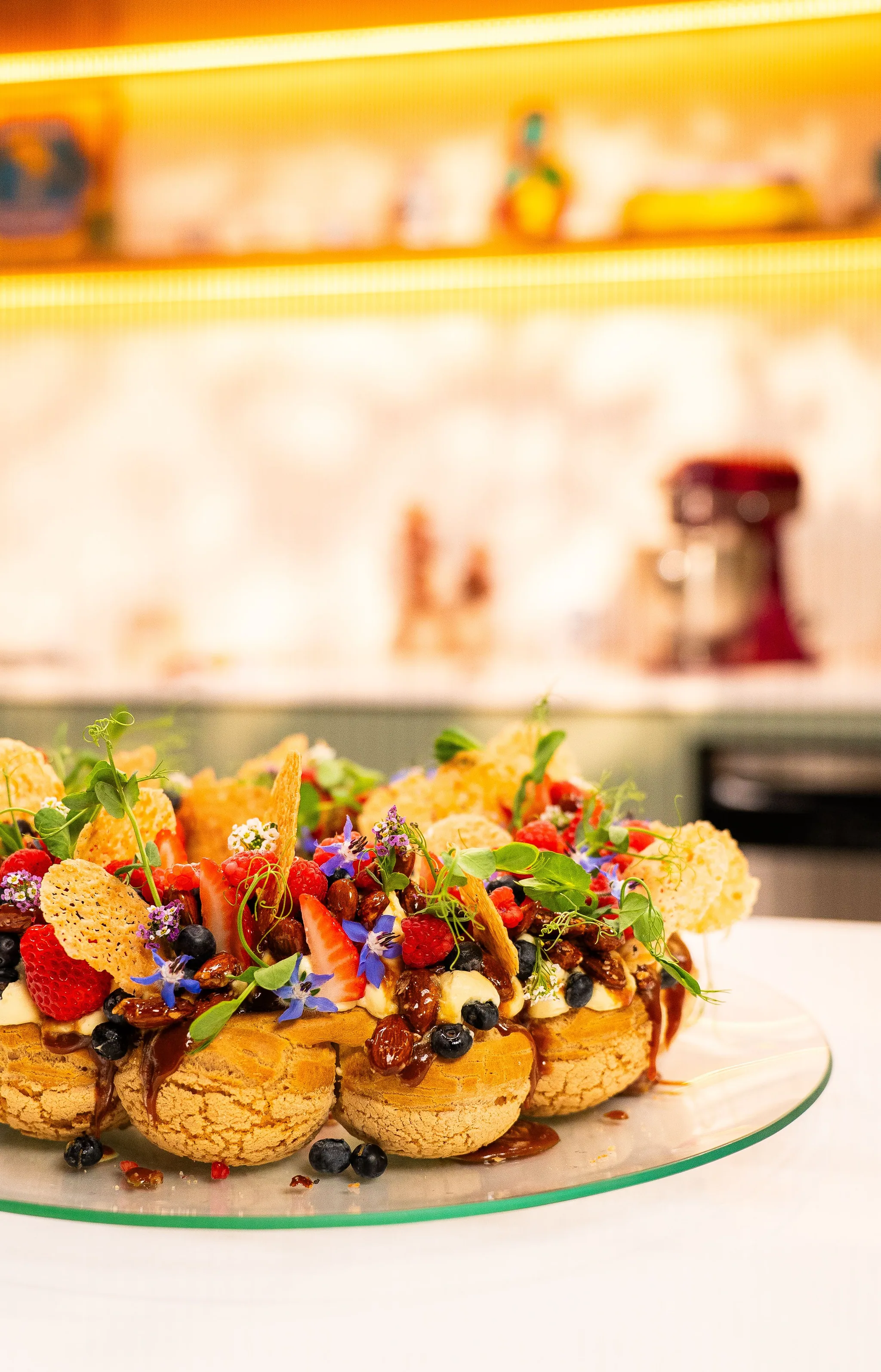 Dessert with red berries, edible flowers and crisp wafers, already plated on the counter.